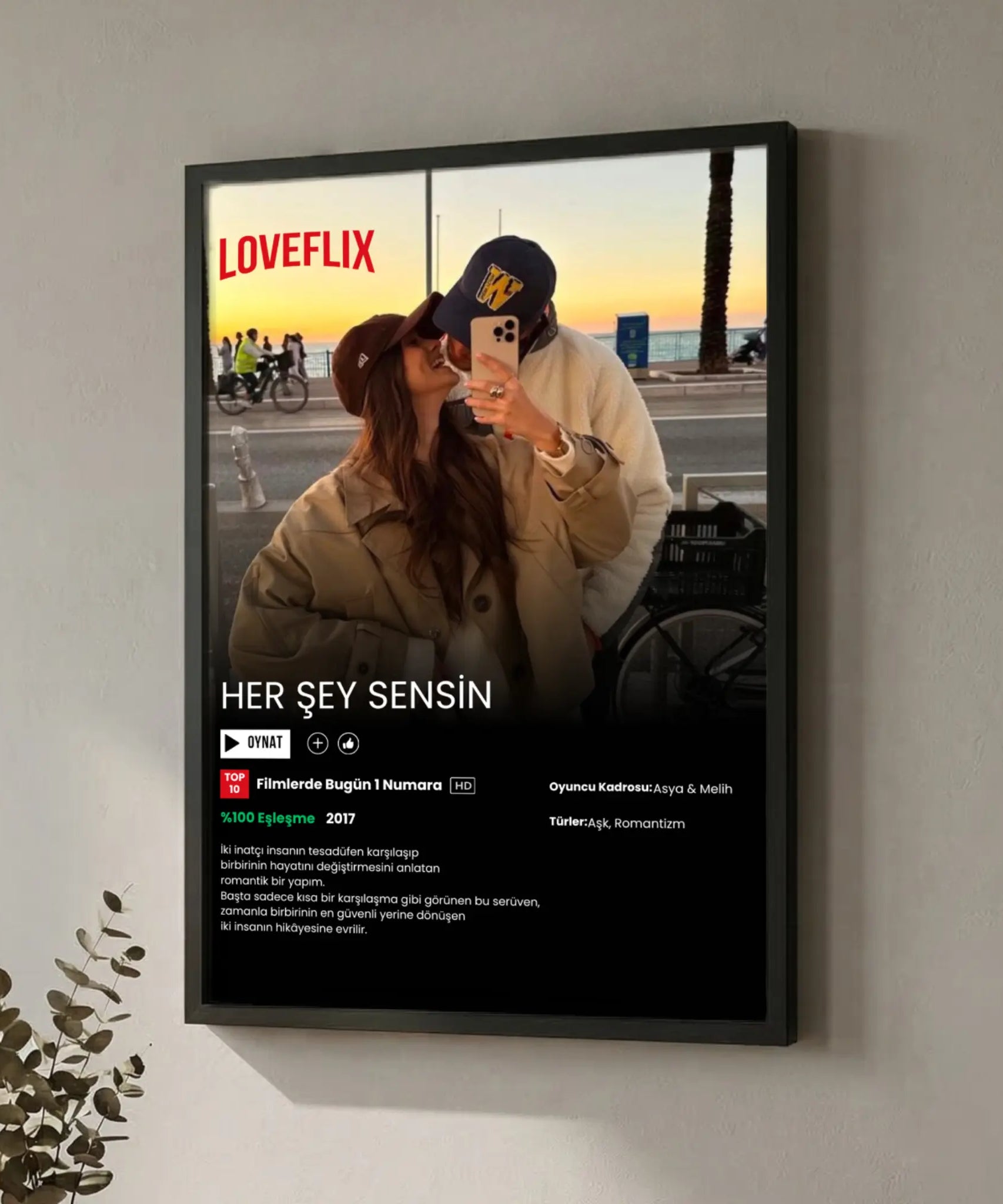 Siyah ahşap çerçeveli, kişiselleştirilebilir yazılar ve fotoğraf içeren kişiye özel Loveflix film afişi tablosu.